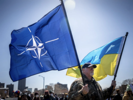 A man at the Hands Off protest against Trump in Minnesota is holding flags of Ukraine and NATO.